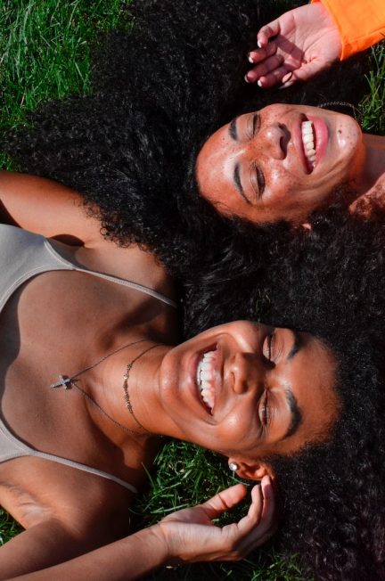 two women lying on green grass